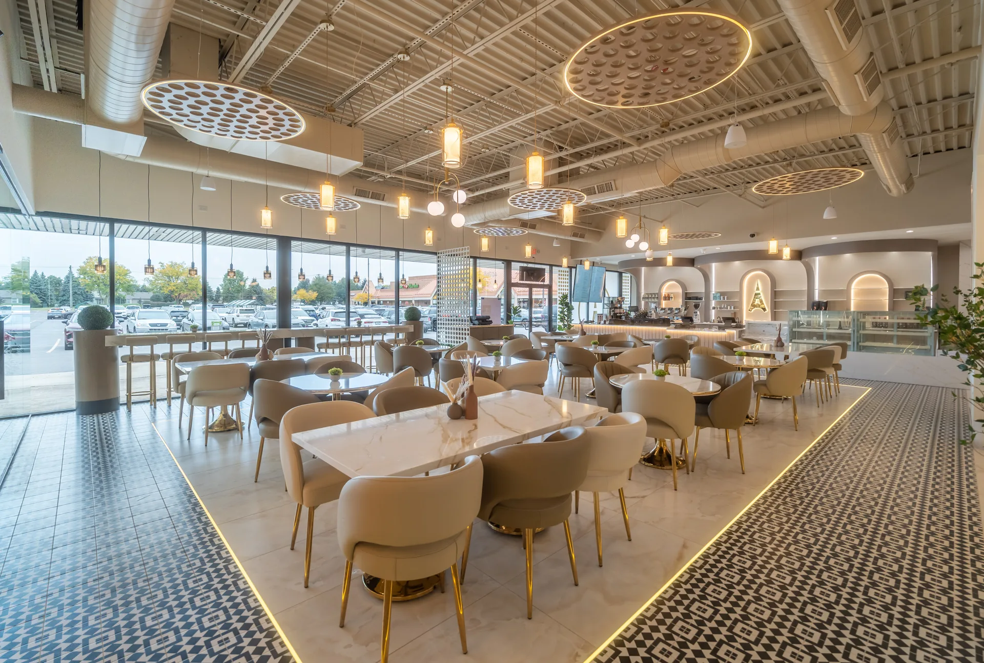 Inside Paris Café — marble tables, curved taupe chairs and a gold-lit mosaic floor beneath the pendant lights
