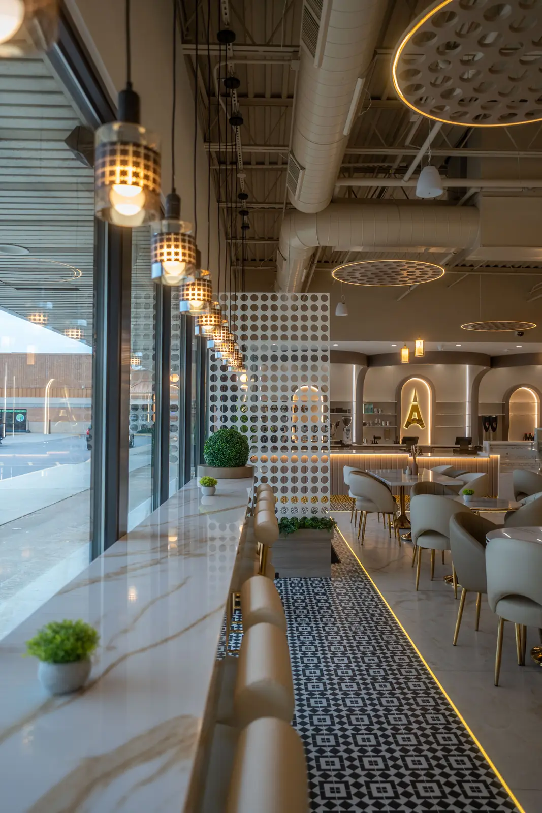 The marble window bar at Paris Café, lit by glass pendants above a gold-edged mosaic floor